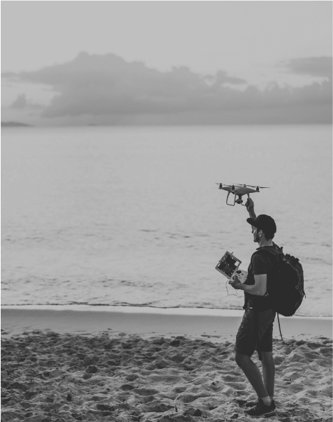 personne tenant un drone en bord de mer